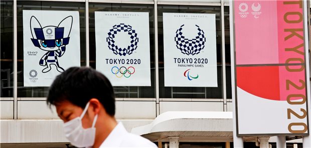 Mann mit Mund-Nasen-Schutz vor Plakaten für die Olympischen Spiele in Tokio.