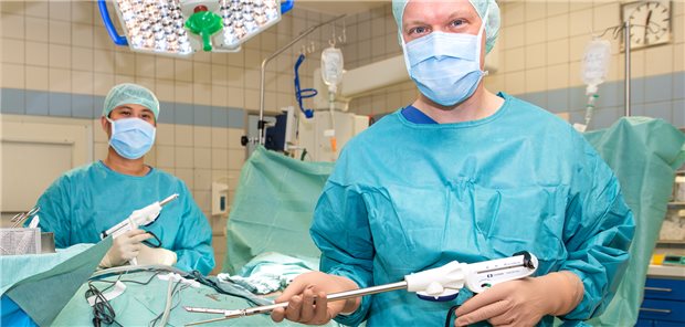 Marc Dominic Villa (links), Gesundheits- und Krankenpfleger im Operationsdienst, und Dr. Jonas Dohmen, Facharzt der Klinik für Chirurgie am UKB, mit einem Klammernahteinweggerät im OP.