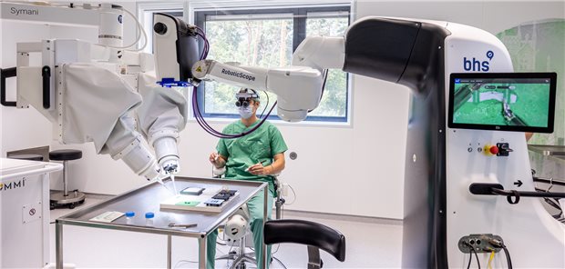 Maximilian Kückelhaus präsentiert bei einem „Trockentraining“ das neue Verfahren. Der Operationsroboter (rechts) ist mit einem robotischen Mikroskop (links) vernetzt.