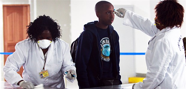 Ebola ist kein Grund für planlose Therapie-Versuche Medizinisches Personal misst die Temperatur eines Reisenden, um eine Ebola-Infektion aufzuspüren.
