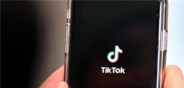 Ein Smartphone wird in die Höhe gehalten. Auf dem Bildschrim ist das TikTok-Logo zu sehen.
