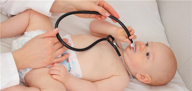Ein Baby spielt bei der Vorsorgeuntersuchung bei der Kinderärztin mit einem Stethoskop.