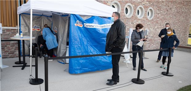 Schnell mal in die Drogerie, um auf Corona testen zu lassen? Menschen stehen während der Vorstellung von Corona-Schnelltest-Zentren der Drogeriemarktkette dm vor einem Testzelt in Karlsruhe an.