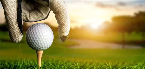 Eine Hand legt sich einen Golfball zurecht.