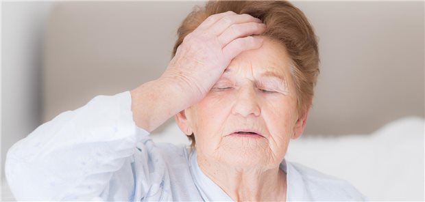 Eine ältere Frau hält sich die Hand an den Kopf. 