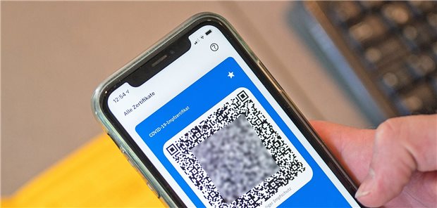 Corona-Genesener will Impfnachweis – eine Odyssee! CoVPass-App in der Hand, im Hintergrund das gelbe Impfbuch.