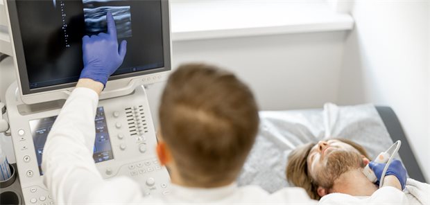 Ein Arzt führt eine Carotis-Sonografie bei einem jungen Mann durch. 