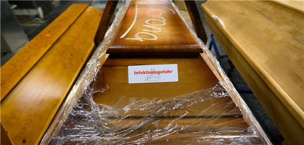 Mehr COVID-Tote in Bundesländern mit niedriger Impfquote Mit Kreide geschrieben steht „Corona“ auf einem Sarg, der vor dem Einäscherungsofen eines Krematoriums steht. Die Zahl der Corona-Toten je 100.000 Einwohner variiert zwischen den Bundesländern stark – dabei fällt die Korrelation mit der jeweiligen Impfquote auf.