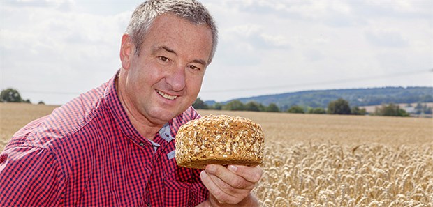 Nach Herzinfarkt viel Vollkorn! Mit Vollkornbrot im Getreidefeld: Experten empfehlen eine tägliche Mindestmenge an Ballaststoffen von 25 g für Frauen und 38 g für Männer.