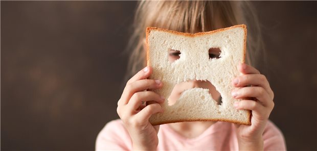  ein Kind hält eine traurige Scheibe Brot in seinen Händen