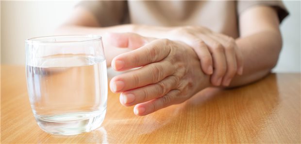 Hand greift nach einem Glas Wasser.
