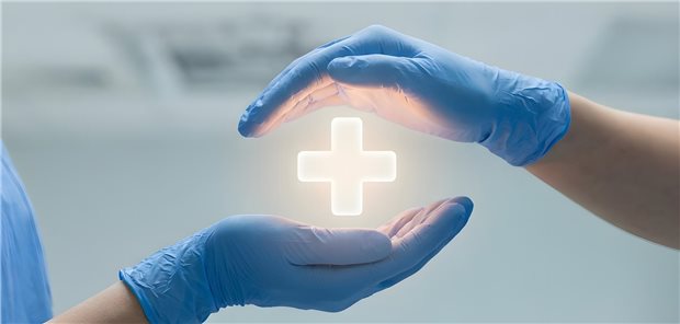 ein medizinisches Kreuz zwischen zwei Händen