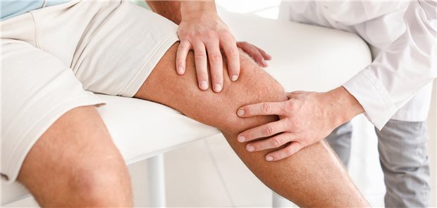 Ein Arzt untersucht in einer Praxis einen Mann mit Gonarthrose für die Ausarbeitung eines Behandlungsplanes.