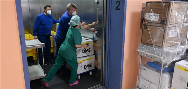 Wie eine Frankfurter Klinik im laufenden Betrieb ihr neues Passivhaus bezieht Mitarbeiter einer Logistikfirma schieben Umzugskisten der Kardiologie in einen Aufzug des alten Klinikums.