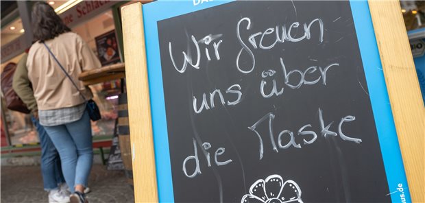 Wie beendet man eine Pandemie? München: Ein Schild mit der Aufschrift „Wir freuen uns über die Maske“ steht vor einem Geschäft auf dem Viktualienmarkt. Seit Anfang April müssen Masken in den meisten Teilen Deutschlands zumindest beim Einkaufen nicht mehr getragen werden. Nur eine der Corona-Maßnahmen, die aufgehoben wurden.