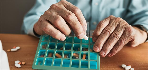Ein alter Mann sortiert seine Tabletten. 
