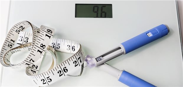 Ein Maßband und zwei Injektionspens liegen auf einer Waage.