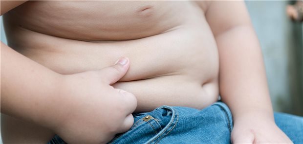 Adipöser Junge überprüft wie viel Fettgewebe zu viel er am Bauch hat.