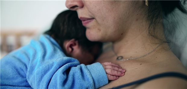 Eine Mutter hält ihr Neugeborenes im Arm. 