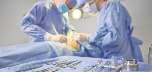Zwei Operateure am Patienten, davor ein Tablett mit Op-Besteck.