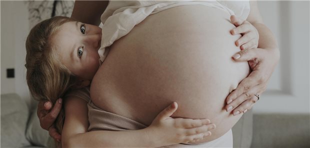 Kind küsst Babybauch.