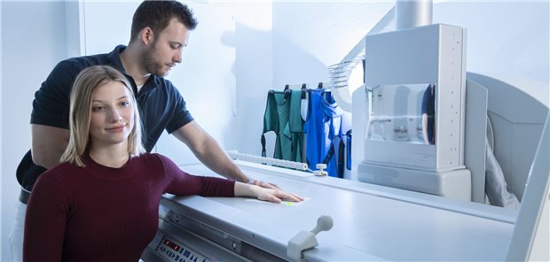 Arzt positioniert Hand von Patientin auf dem Röntgentisch.