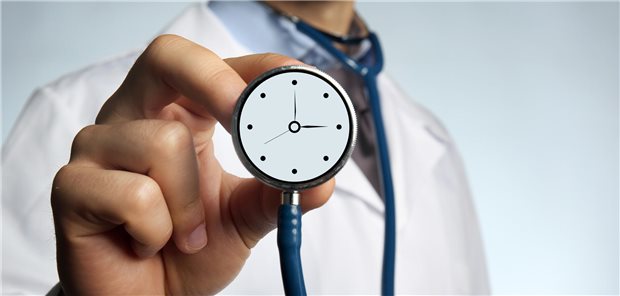 Ein Arzt halt ein Stethoskop in der Hand, auf der eine Uhr zu sehen ist.