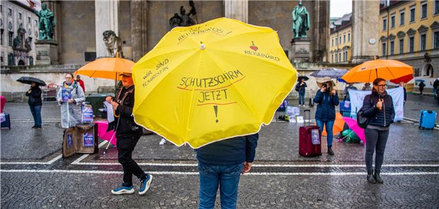 Nicht nur Reiseveranstalter, wie hier bei einer Demonstration in München, benötigten im Frühjahr einen Schutzschirm, auch bei manchen Arztpraxen regnete es kräftig rein in die Praxisumsätze. Die aktuellen Pläne, rückwirkend ab 1. Januar einen Ausgleichsmechanismus für KVen zu erlauben, reichen der KBV aber nicht aus.