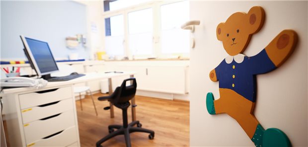 Einblick in Behandlungszimmer mit Teddybär an der Tür.