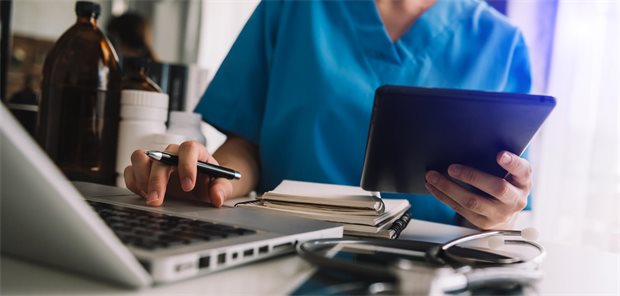 Ärzti arbeitet mit Laptop und Tablet