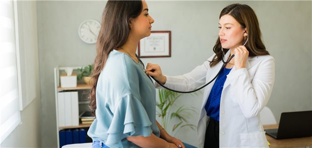 Eine Ärztin hört während einer medizinischen Konsultation in ihrer Praxis die Lunge einer Patientin ab.