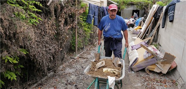 Oleksandr fährt mit der Schubkarre den stinkenden Schlamm weg, den er aus seinem Haus schaufelt.