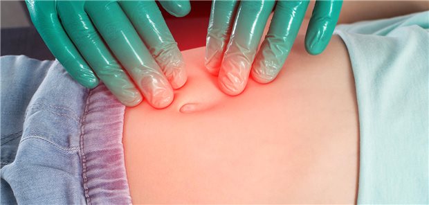 Behandschuhte Hände untersuchen den Bauch eines Kindes.