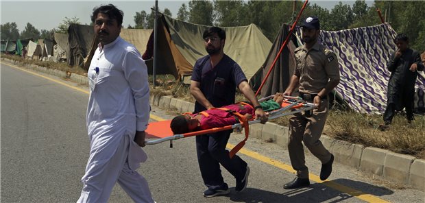 900 Gesundheitseinrichtungen bei Überschwemmungen in Pakistan zerstört Pakistanisches Gesundheitspersonal trägt ein krankes Mädchen, das aus seinem von der Flut betroffenen Haus geflohen ist.