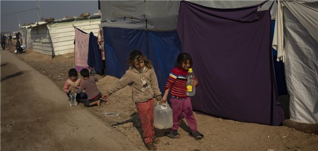 Palästinensische Kinder, die durch die israelische Bombardierung des Gazastreifens vertrieben wurden, tragen Wasser in einem behelfsmäßigen Zeltlager.