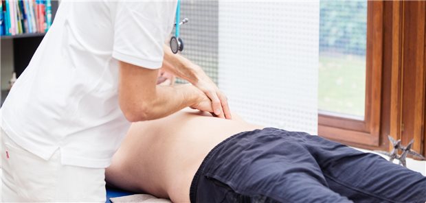 Ein Arzt palpiert den Bauch eines jungen Patienten. 