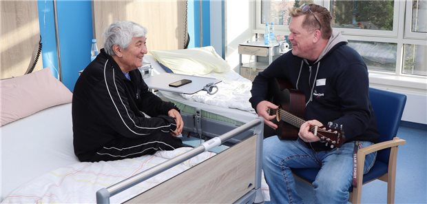Krankenhaus Reinbek: Ein Klinikbeschäftigter mit Zeit zum Zuhören und Kümmern Patient Schumagali Kaschkenow erhält ein kleines Privatkonzert von Guest Relation Manager Dirk Bülow auf dem Patientenzimmer im Reinbeker St. Adolf Stift.