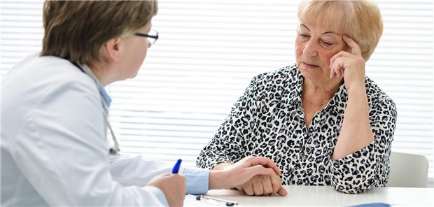 Arzt hält die Hand einer Frau.