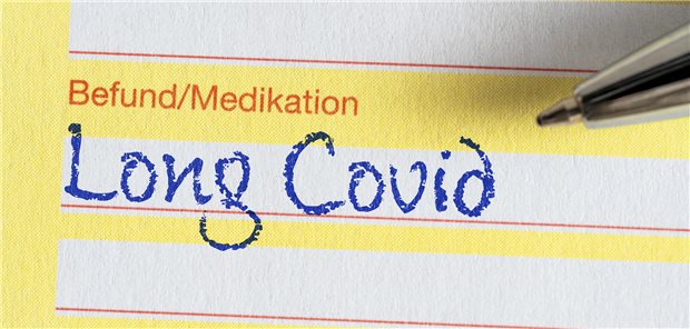 Ein Mensch schreibt Long-COVID als Befund auf ein Dokument.