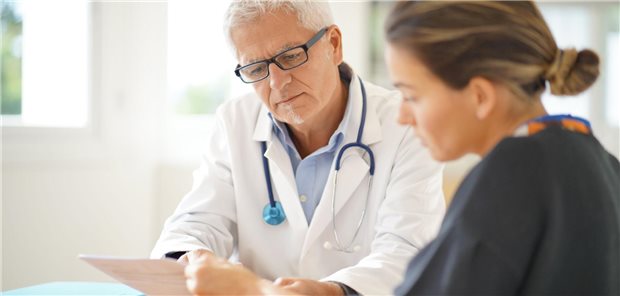 Arzt spricht mit einem Patienten. Beide sind von hinten zu sehen.
