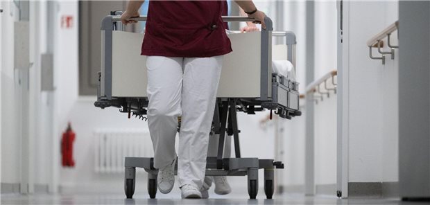 Pflege im Akkord: Eine Krankenpflegerin und ein Krankenpfleger schieben ein Krankenbett durch den Gang einer Station eines Krankenhauses. Nur wenn es schnell geht und ein Krankenhaus voll ausgelastet ist, wird noch Geld verdient.
