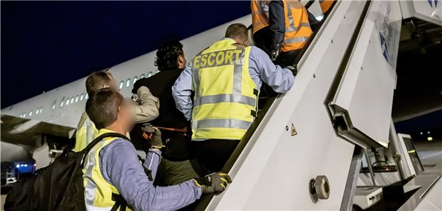 IPPNW kritisiert Abschiebepraxis bei Flüchtlingen harsch Polizeibeamte begleiten einen Afghanen in Handfesseln auf dem Flughafen Leipzig-Halle in ein Charterflugzeug.
