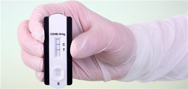 Rasante Zunahme bei COVID-19 als Berufskrankheit Symbolbild: ein Arzt hält einen positiven Corona-Test in der Hand