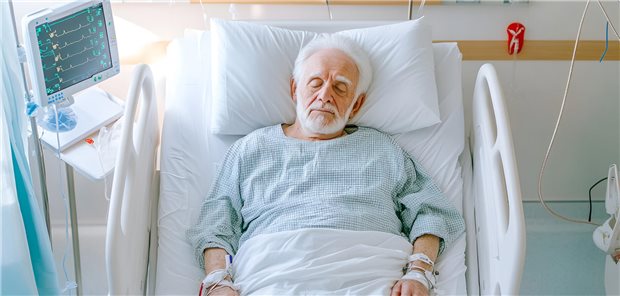 Ein älterer Mann liegt mit geschlossenen Augen nach einer Operation in seinem Krankenbett.