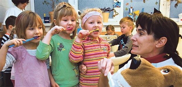 Prävention verstärkt in Kitas, Betrieben und Co. Prävention in der Lebenswelt Kita: Eine Zahnärztin erklärt mittels einer Handpuppe, wie Zähne richtig geputzt werden.