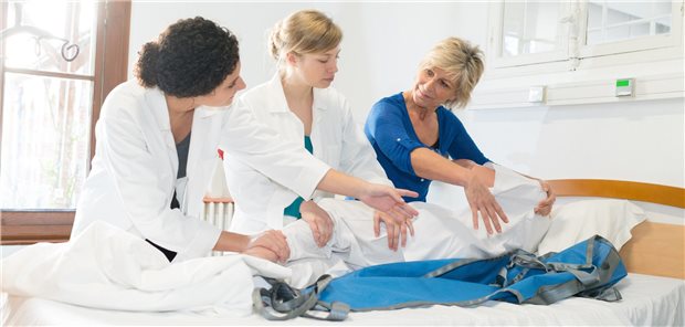 Ausbilderin zeigt jungen Pflegeazubis die richtige Technik.