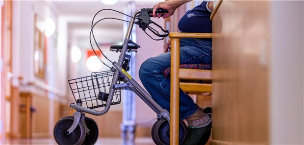 Ein Bewohner sitzt mit seinem Rollator auf einem Flur in einem Pflegeheim.
