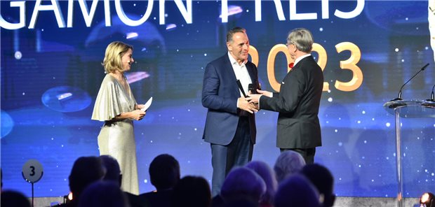 Professor Erland Erdmann übergibt Jean-Luc Delay (M.) von der Geschäftsführung des Unternehmens Takeda Pharma GmbH, den Galenus-Preis für Qdenga® in der Kategorie Primary Care. Links steht Moderatorin Yve Fehring.