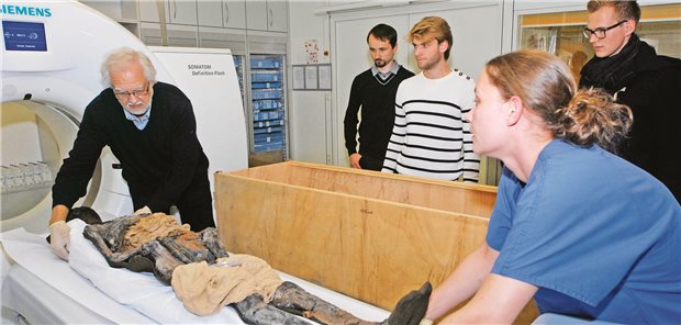 Professor Michael Schultz bereitet mit Unterstützung eine Mumie für eine Untersuchung vor.
