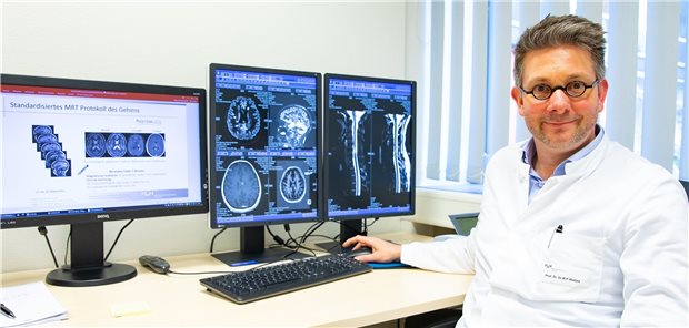 Professor Mike P. Wattjes, federführender Autor der neuen MRT-Leitlinie, vor zwei Monitoren mit Schichtaufnahmen von veränderten Hirnstrukturen durch Multiple Sklerose.